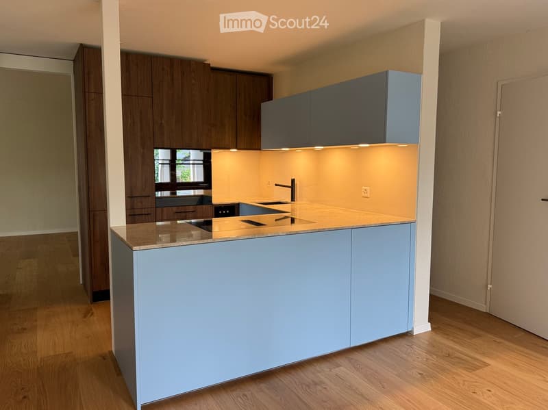 Modern kitchen with light blue and dark wood cabinets, a central island, and a sleek countertop.