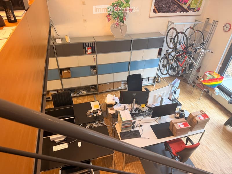 Office space with desks, chairs, computers, shelves, bicycles, and a clock.