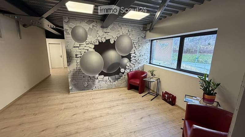 Modern, minimalist room with wooden flooring, large window, red sofa, small table, and decorative wall art.