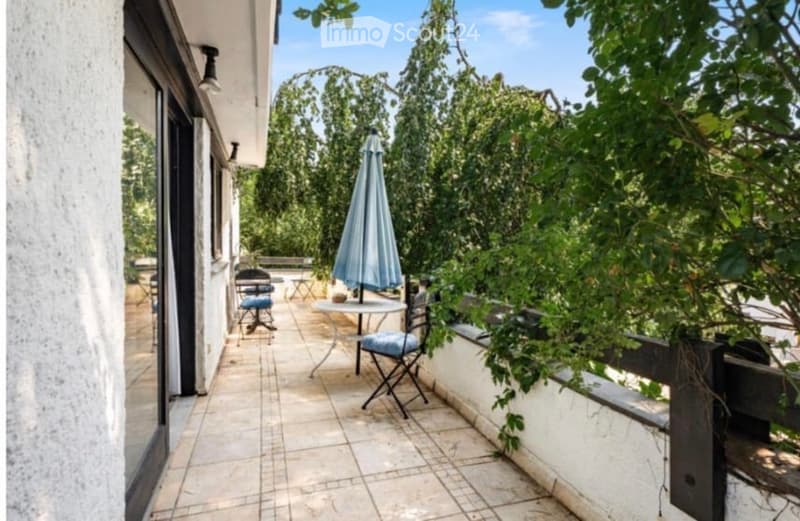 Balcony with tiled floor, white walls, outdoor furniture including a table, chairs, and an umbrella.