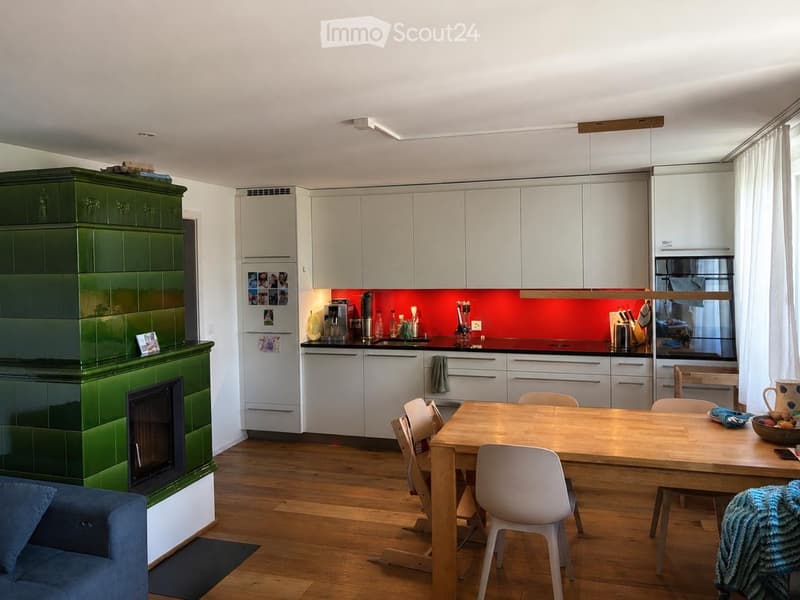 Open-plan living and dining area with a modern kitchen, fireplace, and dining table with chairs.