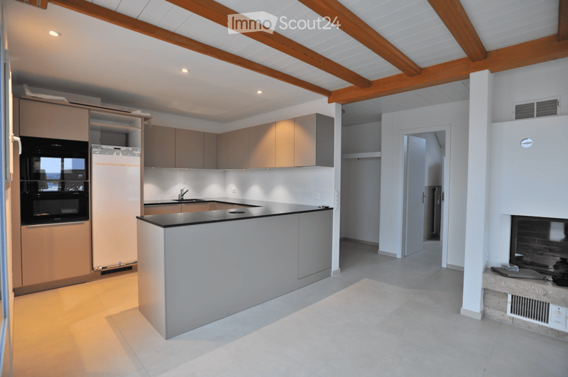 Modern kitchen with light wood cabinets, stainless steel appliances, island, and built-in sink.