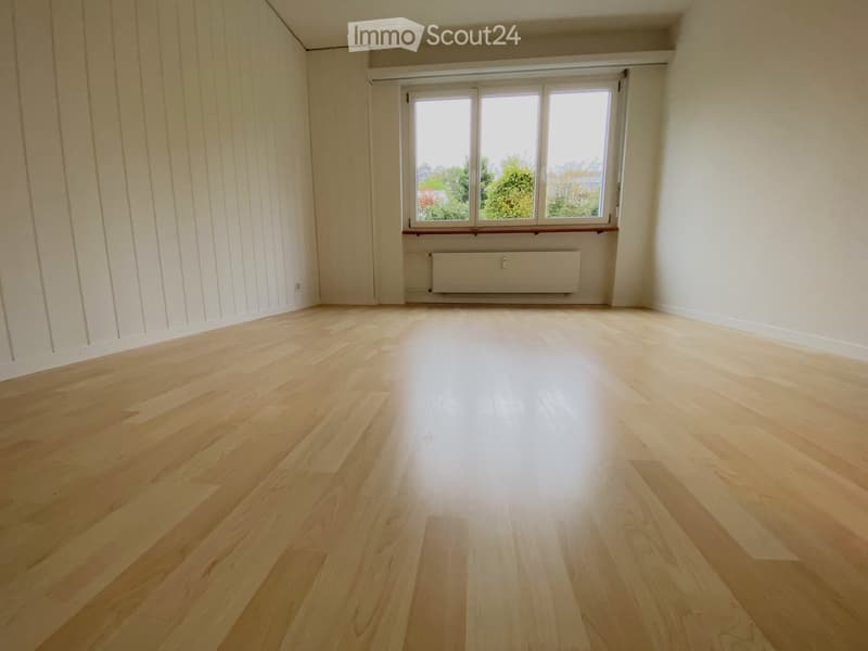 an empty room with hardwood floors and a window with a white exterior frame