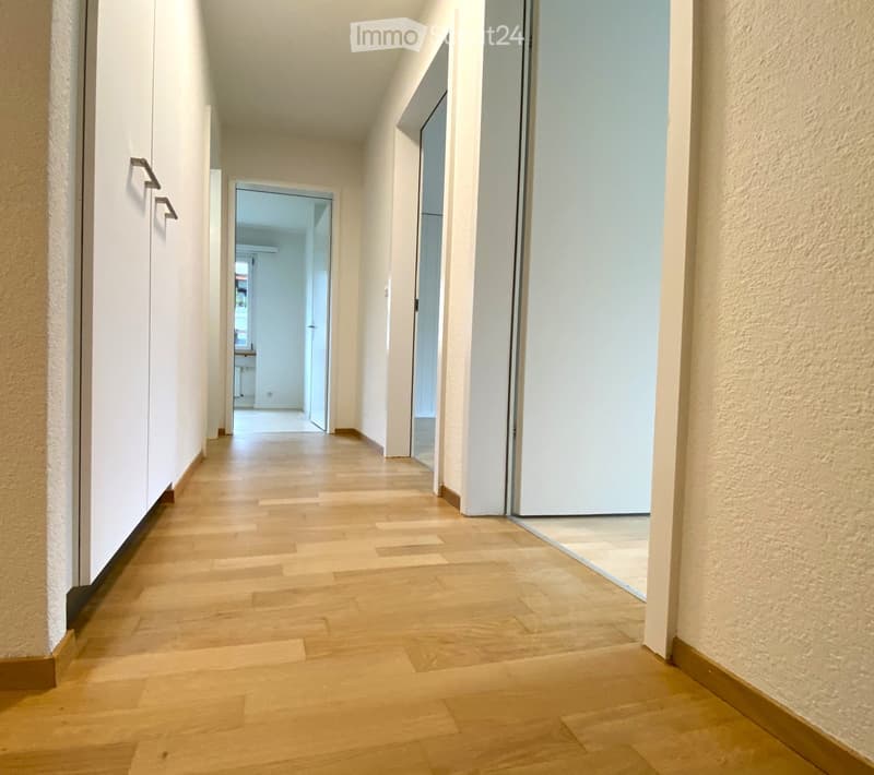 long hallway, white walls, wooden floor, white doors