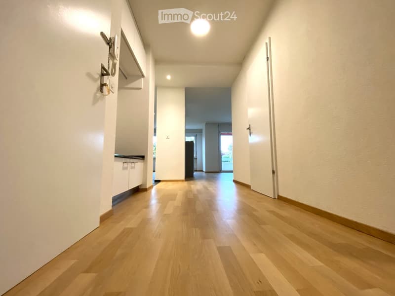 hardwood floor, white walls, hallway leading to kitchen and other rooms