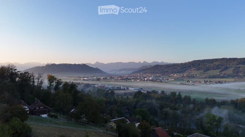 aerial view of a valley with houses, mountains, and a runway