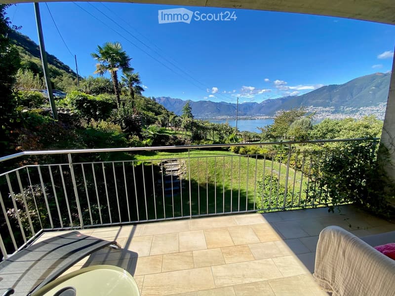 Balcony with a scenic mountain and lake view, featuring a tiled floor, metal railing, and outdoor furniture including a chair and table.