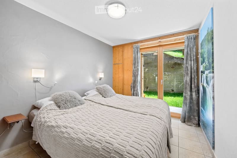 Cozy bedroom with a double bed, nightstand, large window with a scenic view, and a picture frame on the wall.