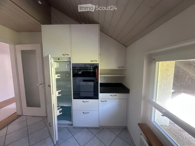 Modern kitchen with white cabinets, a refrigerator, and an oven. The space features tiled flooring and a window allowing natural light.