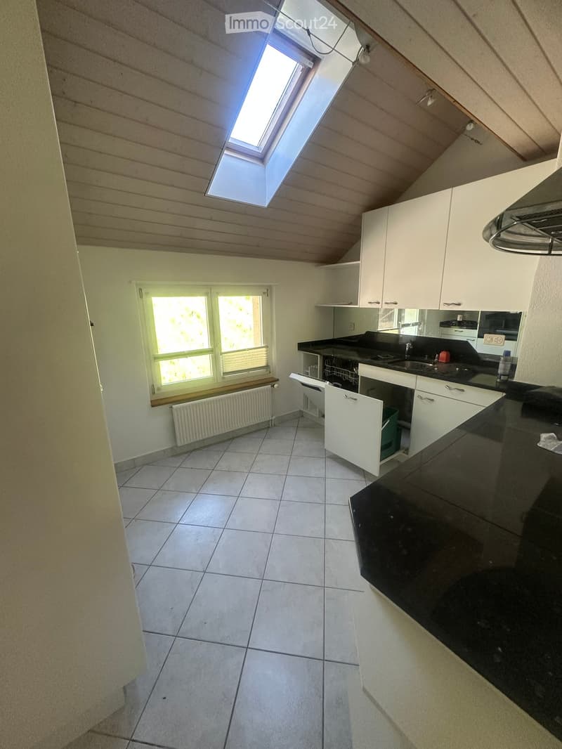 Modern kitchen with white cabinets, black countertop, tiled floor, and a skylight window above the sink.
