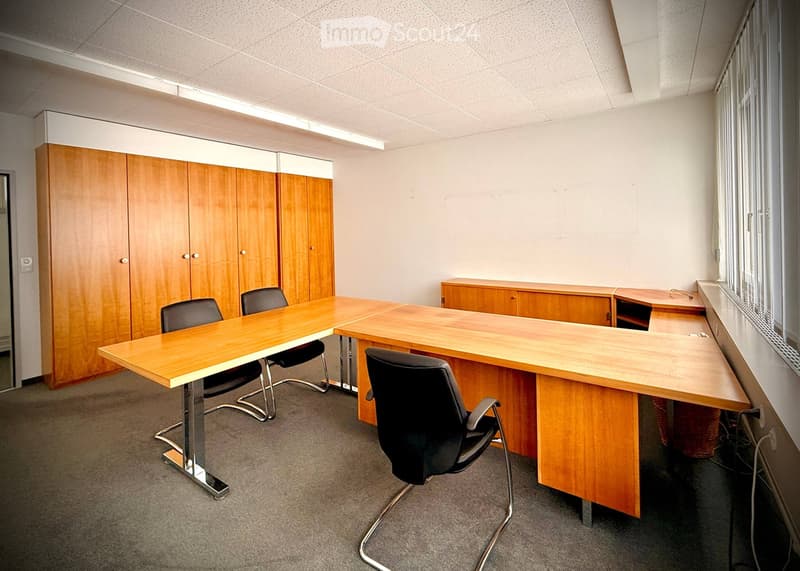 Office space with wooden tables, black chairs, and wooden cabinets.