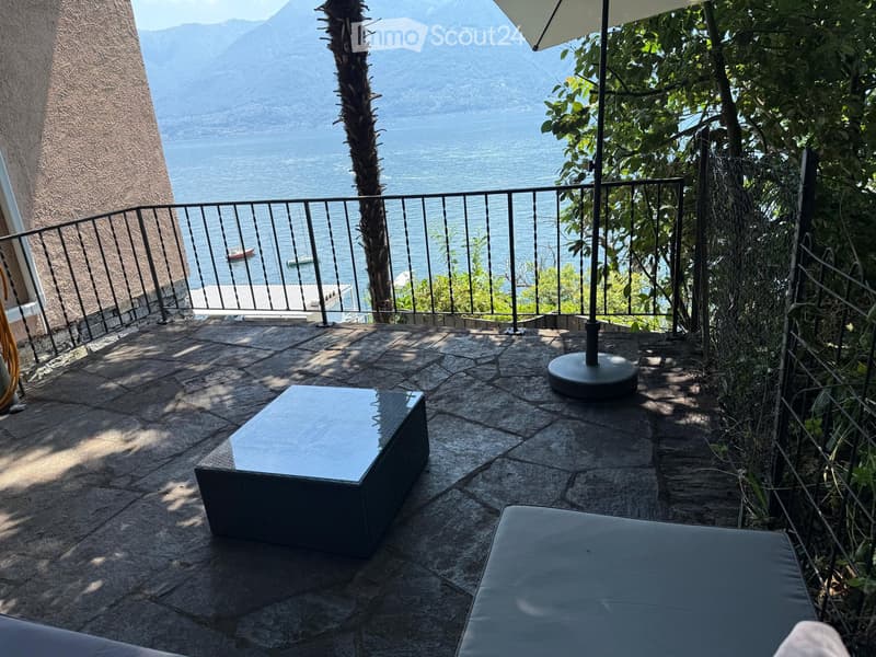 Balcony with stone floor, outdoor furniture, and scenic lake view.
