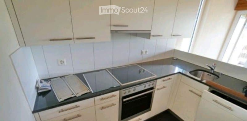 Modern kitchen with white cabinets, black countertops, and built-in appliances including an oven and sink.