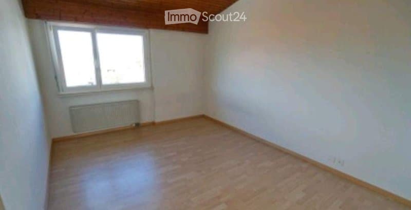 Empty room with wooden flooring, white walls, a single window, and a radiator below it.