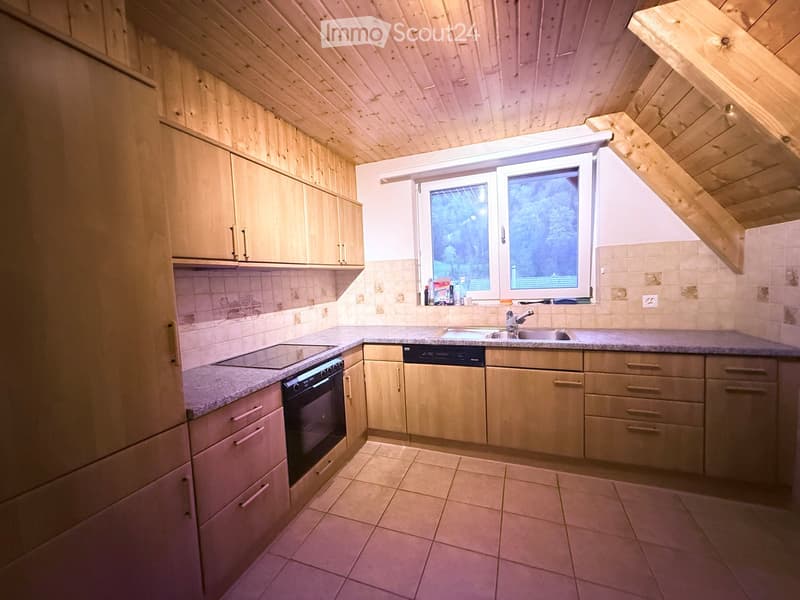 Modern kitchen with wooden cabinets, granite countertops, and stainless steel appliances including an oven and dishwasher. Features a window with a view of the outdoors.