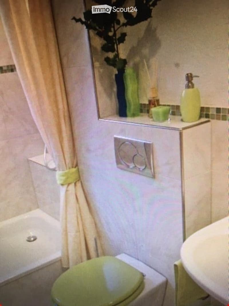 Bathroom with a toilet, sink, mirror, and shower curtain. A soap dispenser and candle are placed on the sink counter.