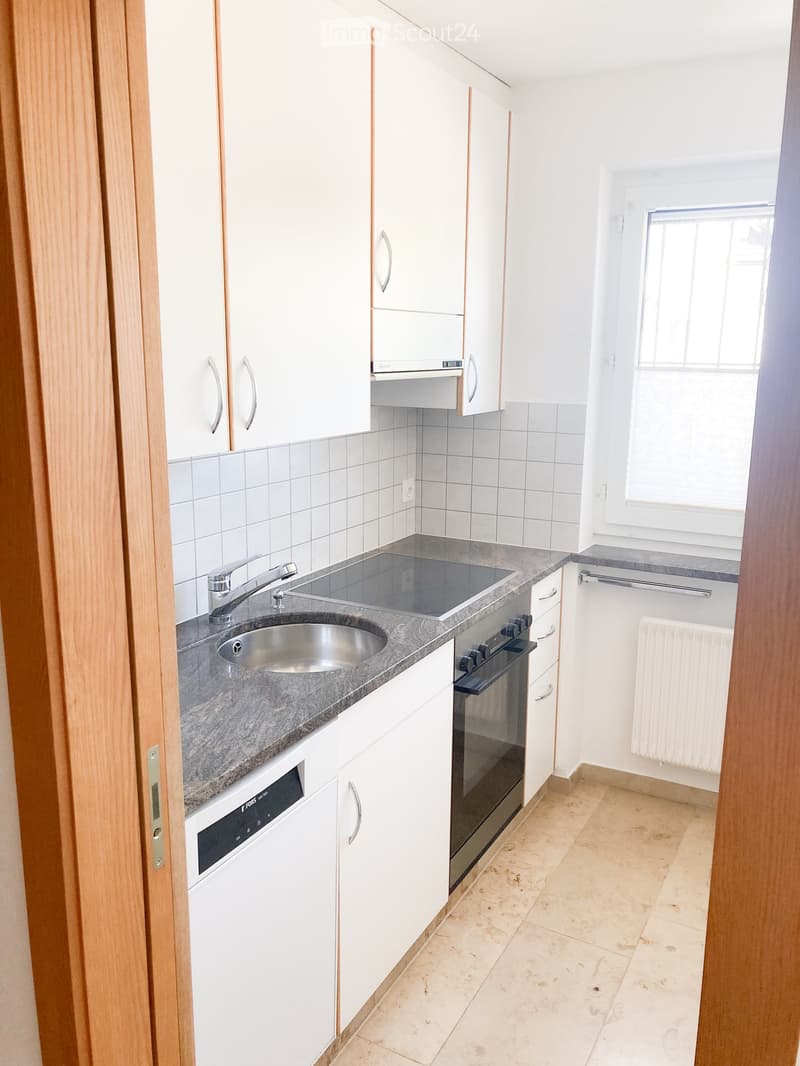 Modern kitchen with white cabinets, stainless steel sink, oven, dishwasher, and granite countertop.