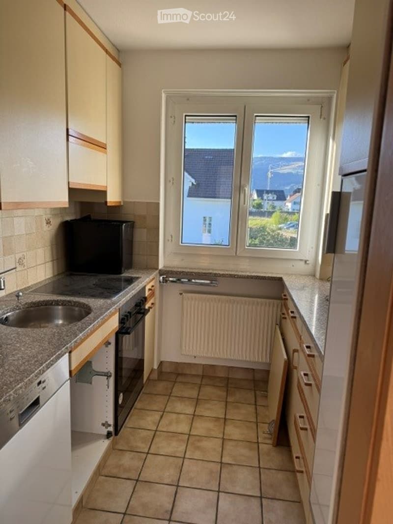 Bright kitchen with tiled floor, granite countertops, and a view of the landscape through large windows. Includes sink, oven, dishwasher, and cabinets.