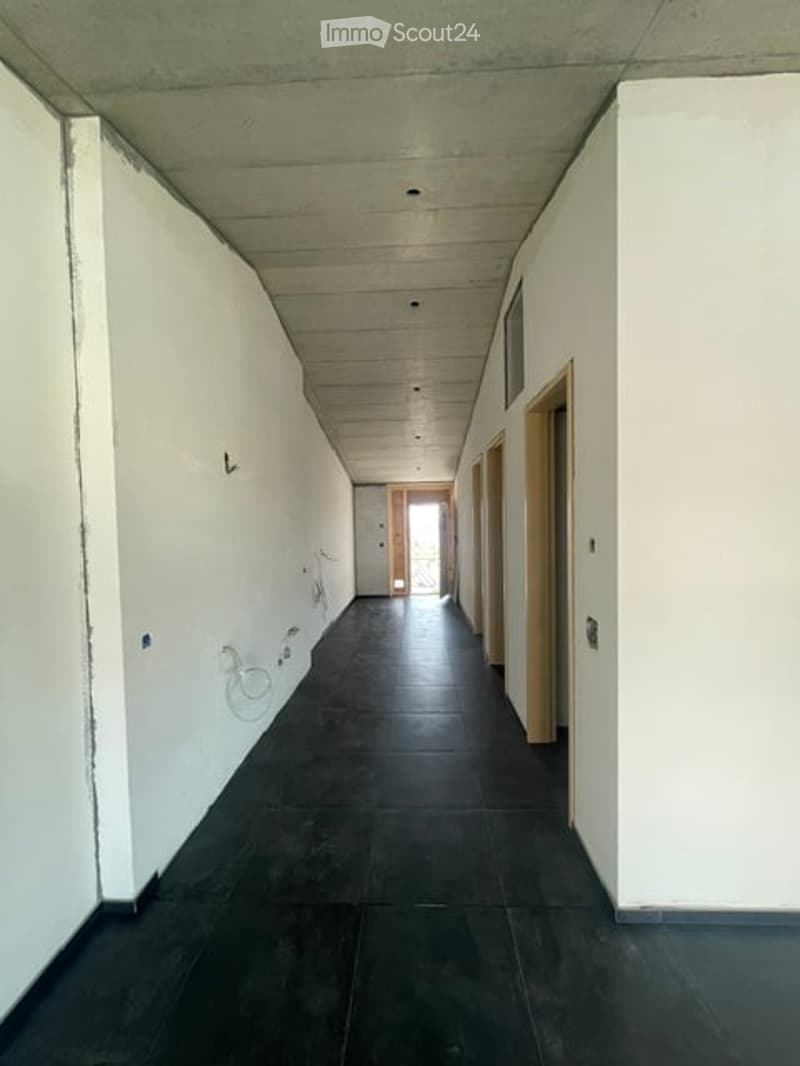 Empty hallway with white walls, dark tiled floor, and wooden doors on both sides.