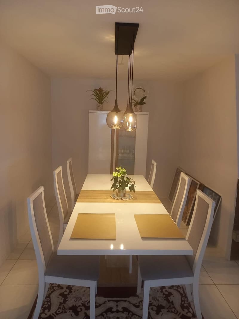 Dining room with a white table and chairs, a white cabinet, and a white ceiling with hanging lamps