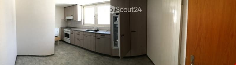 Modern kitchen with grey cabinets, a sink, a fridge, and an oven. The space is well-lit with natural light from a large window.