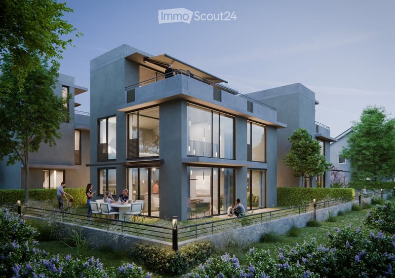 Modern two-story residential building with large glass windows and balconies, surrounded by a landscaped garden with seating area and people enjoying the space.