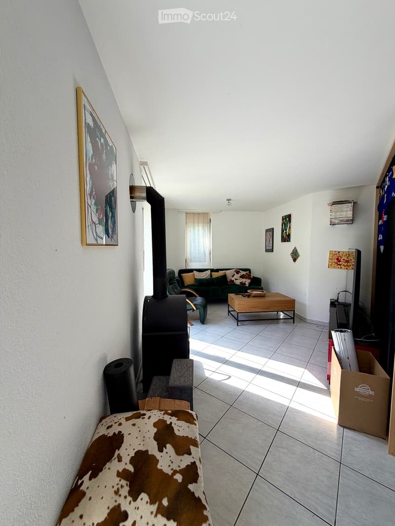 Living room with a tiled floor, fireplace, sofa, coffee table, armchair, and artwork on the walls.
