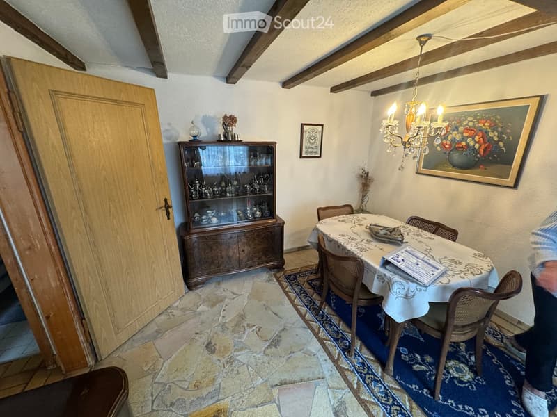 Dining room with a wooden table, chairs, a cabinet, chandelier, and a picture on the wall.