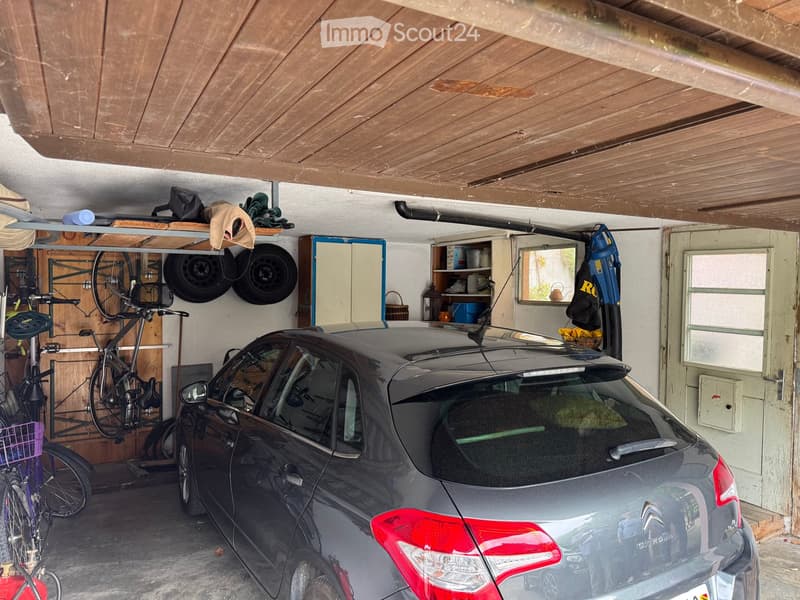 {"visible_features": ["Garage"], "type": "Garage", "objects": [], "description": "Garage with a parked car, bicycles, tires, and storage shelves.", "localized_descriptions": {"EN": "Garage with a parked car, bicycles, tires, and storage shelves.", "DE": "