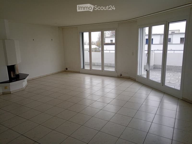 Empty room with tiled floor, fireplace, large windows, and sliding doors leading to a balcony.
