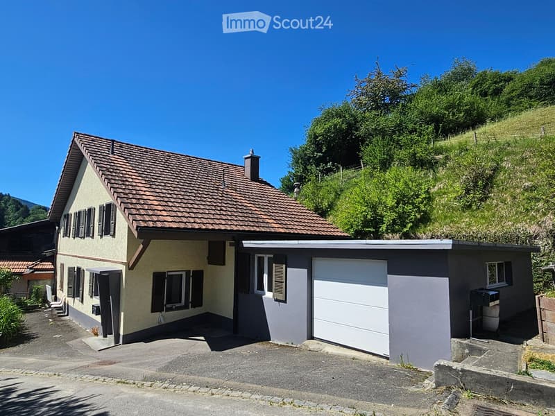 Two-story house with a tiled roof, beige and grey exterior, garage, and raised ground floor.