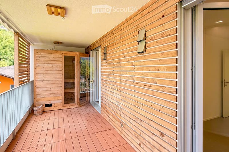 Balcony / Terrace. Balcony with wooden slatted walls, tiled floor, and a small wooden sauna enclosure with glass doors.