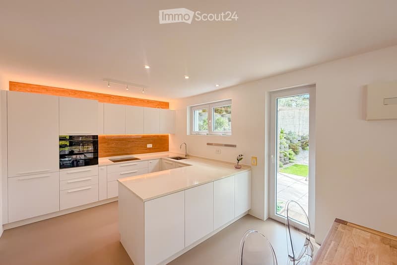 Kitchen. Modern kitchen with white cabinets, a central island, and a wooden accent backsplash. Features a sink, faucet, and an oven integrated into the cabinetry.