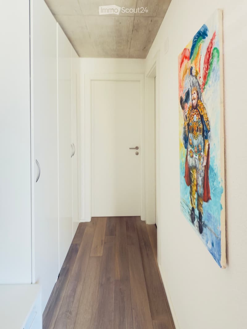 white walls, wooden floor, white door, art on wall, three white closets
