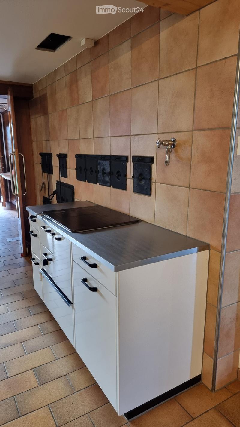 Modern kitchen with white cabinets, an induction cooktop, and beige tiled walls.