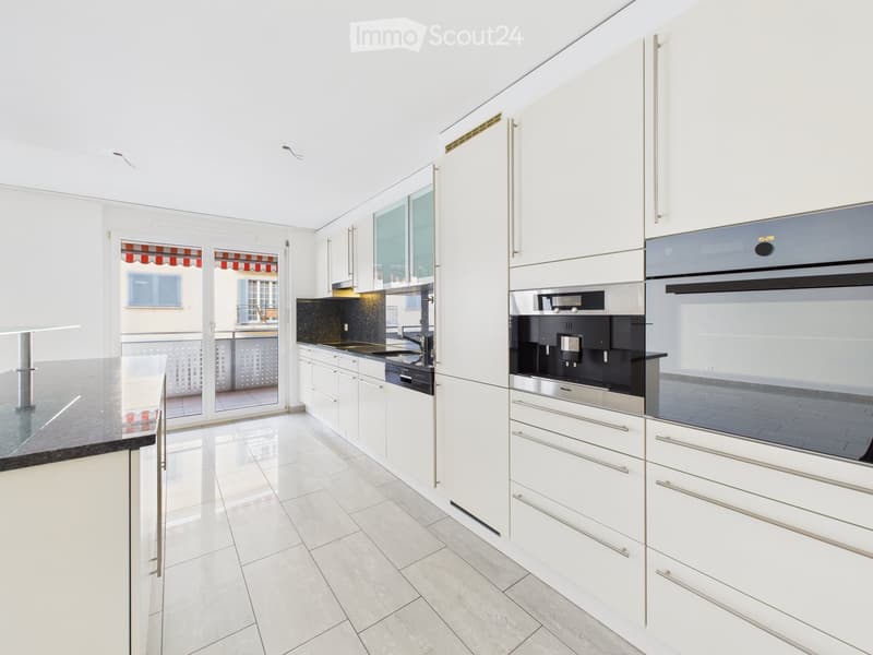 Modern kitchen with white cabinets, stainless steel appliances, and a black countertop.