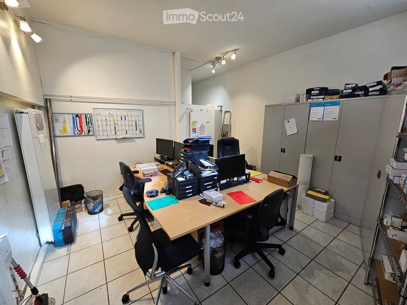 Office space with a wooden desk, two office chairs, computer setup, filing cabinets, whiteboard, and storage units.