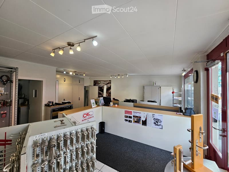 Office space with reception desk, computer, printer, cabinets, key rack, and track lighting.