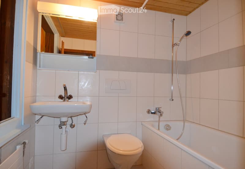 Bathroom with white tiles, white sink, white toilet, bathtub, shower head, mirror, and wooden ceiling.