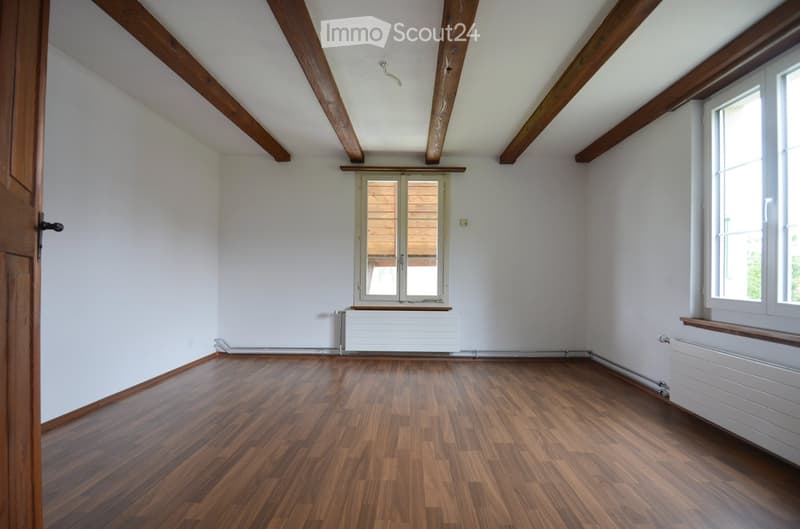 empty room, wooden floor, white walls, wooden beams, two windows, radiators