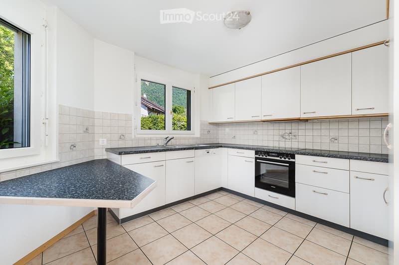 Modern kitchen with white cabinets, granite countertops, and stainless steel appliances, including an oven and sink.