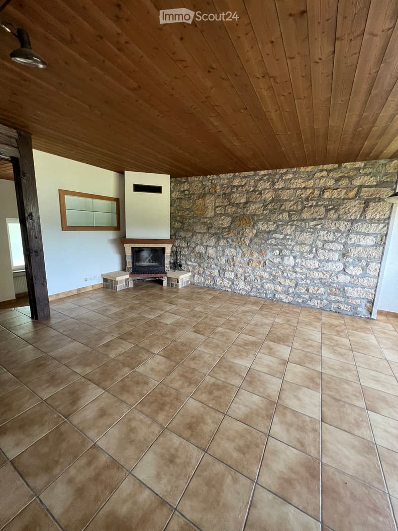 Empty room with wooden ceiling, stone wall, fireplace, and tiled floor.