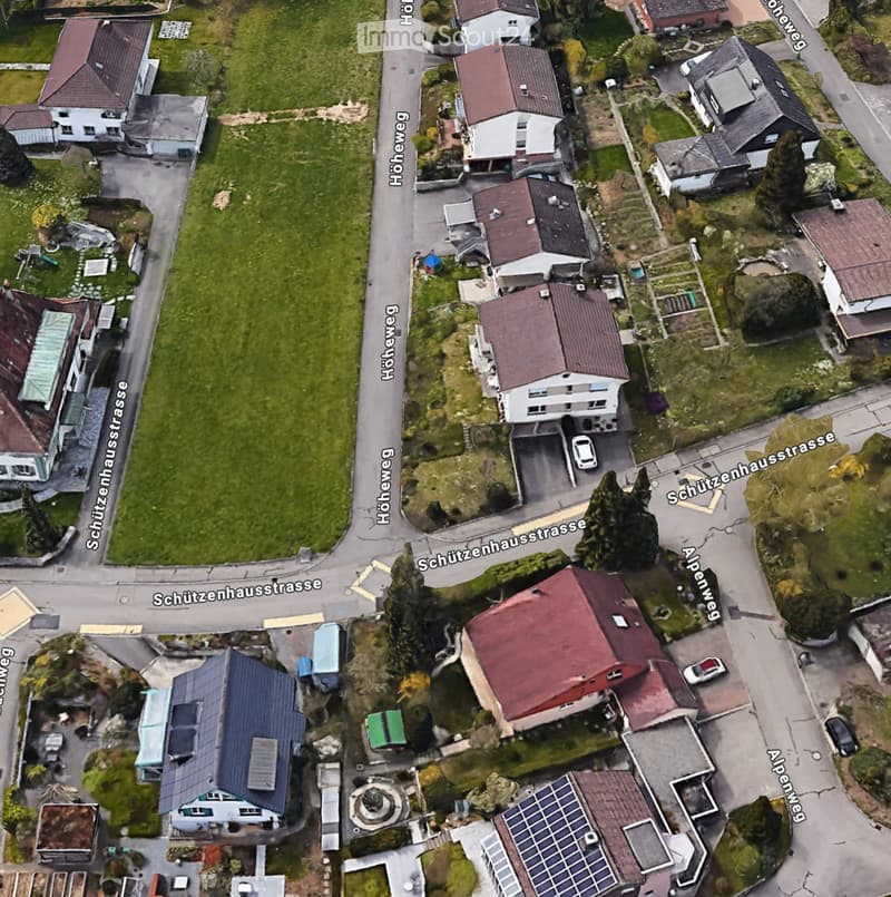 Aerial view of a residential area with multiple houses, driveways, and surrounding greenery.