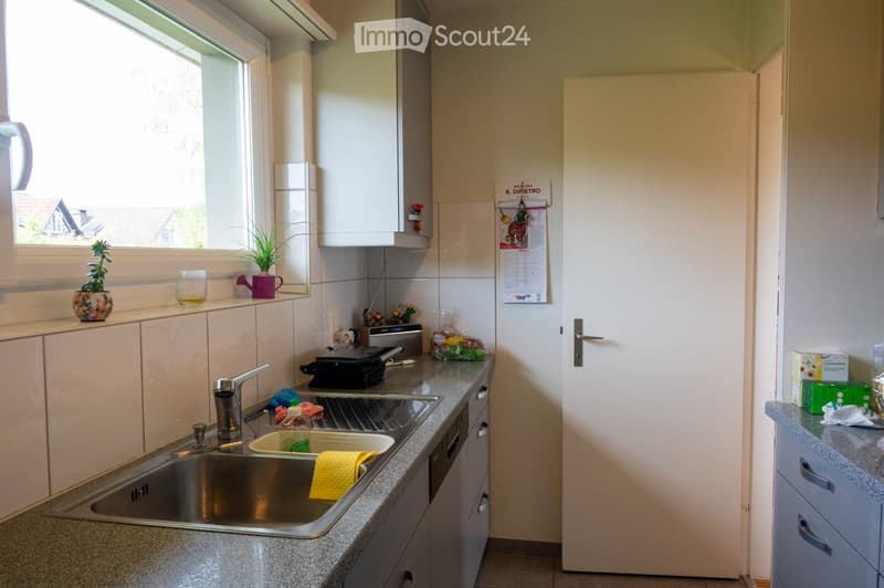 Modern kitchen with granite countertops, stainless steel sink, white cabinets, and various small appliances and decorative items on the counters.