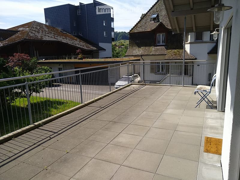 Balcony with tiled floor, metal railing, and a single folding chair.