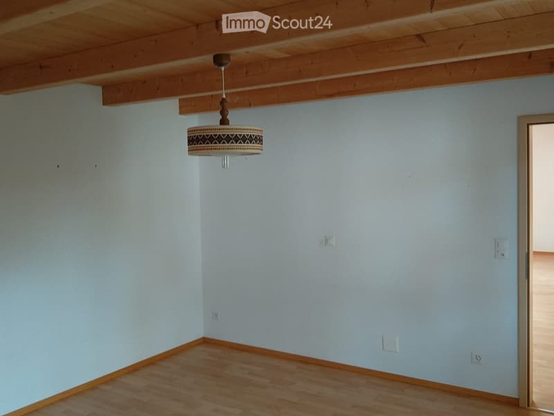 Empty room with light blue walls, wooden floor, and a decorative hanging light fixture.