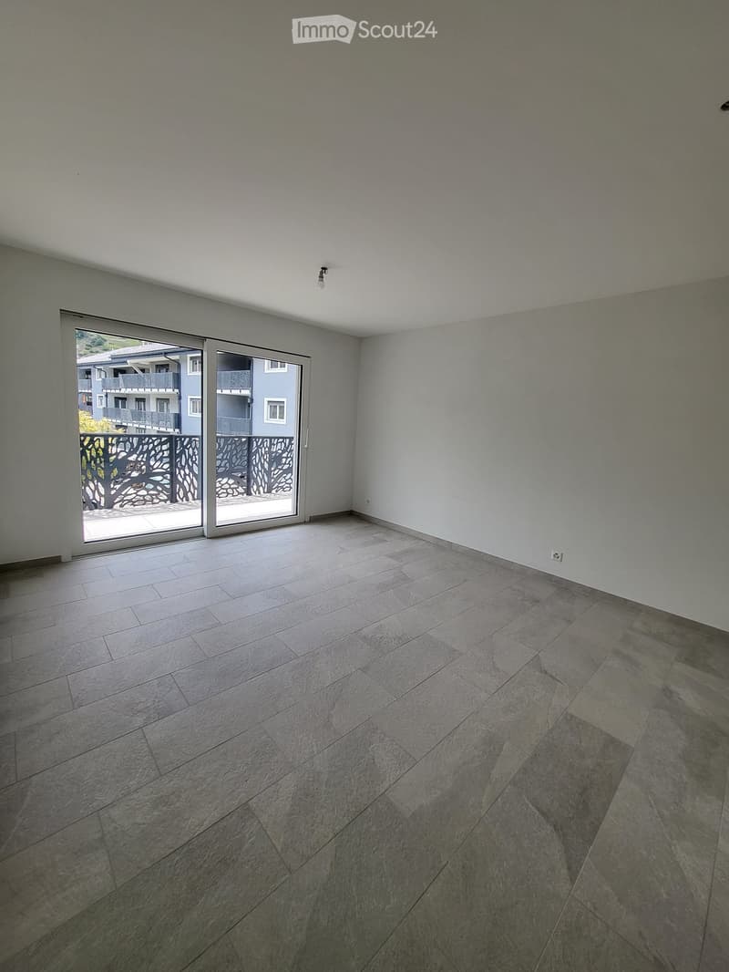Empty room with grey tiled floor, white walls, and large sliding glass door leading to a balcony.