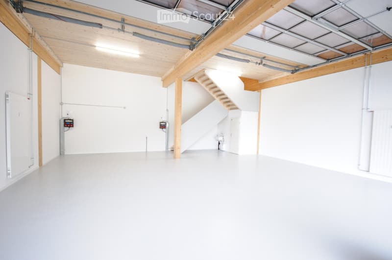 Empty room with white walls, wooden beams, and a staircase leading to an upper level. No furniture or equipment is present.