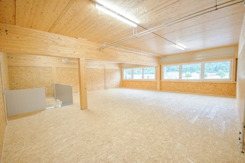 Empty room with wooden walls, ceiling, and floor, large windows, and exposed wooden beams.