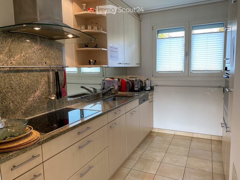 Modern kitchen with granite countertops, white cabinets, stainless steel appliances, and a double sink.